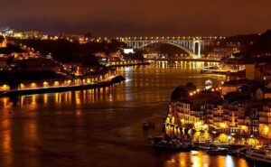 Vue nocturne depuis le Jardim do Mouro à Vila Nova de Gaia, avec la rive du Douro, les édifices illuminés de Porto et le pont d'Arrábida en arrière-plan.