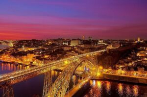 Photo prise du quai de Vila Nova de Gaia, offrant une vue sur les bateaux traditionnels Rabelo, le pont ancestral Dom Luís I de style Eiffel, le quartier historique de Porto sur la rive du Douro, avec en arrière-plan le monastère, classés au patrimoine de l'UNESCO.
